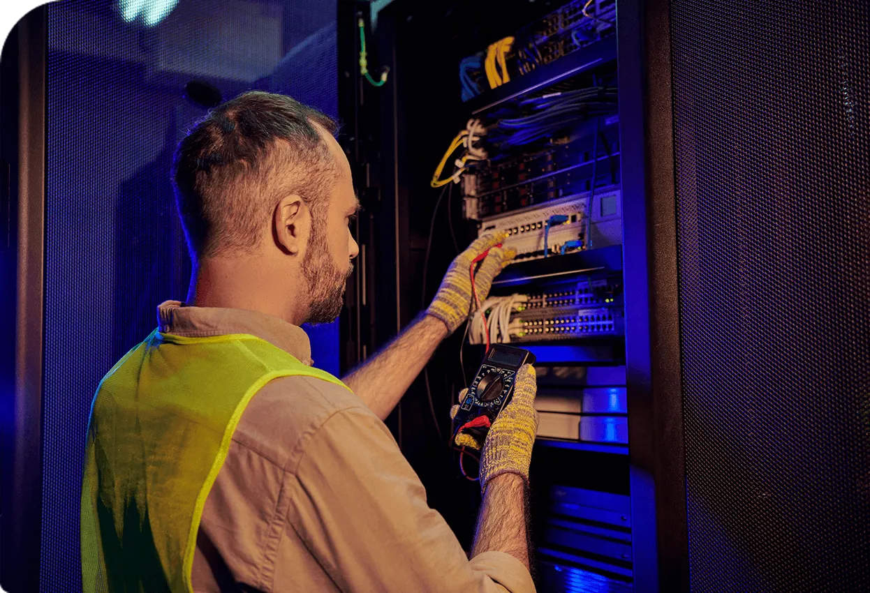 Technician working in a server room, checking network cables with measuring equipment.