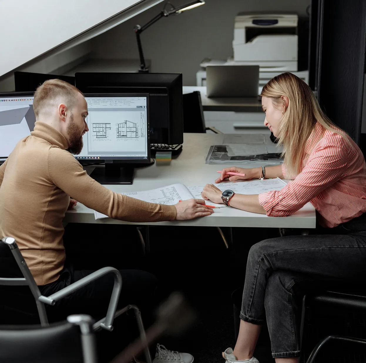 Team reviewing blueprints and 3D models on a computer during a design meeting.