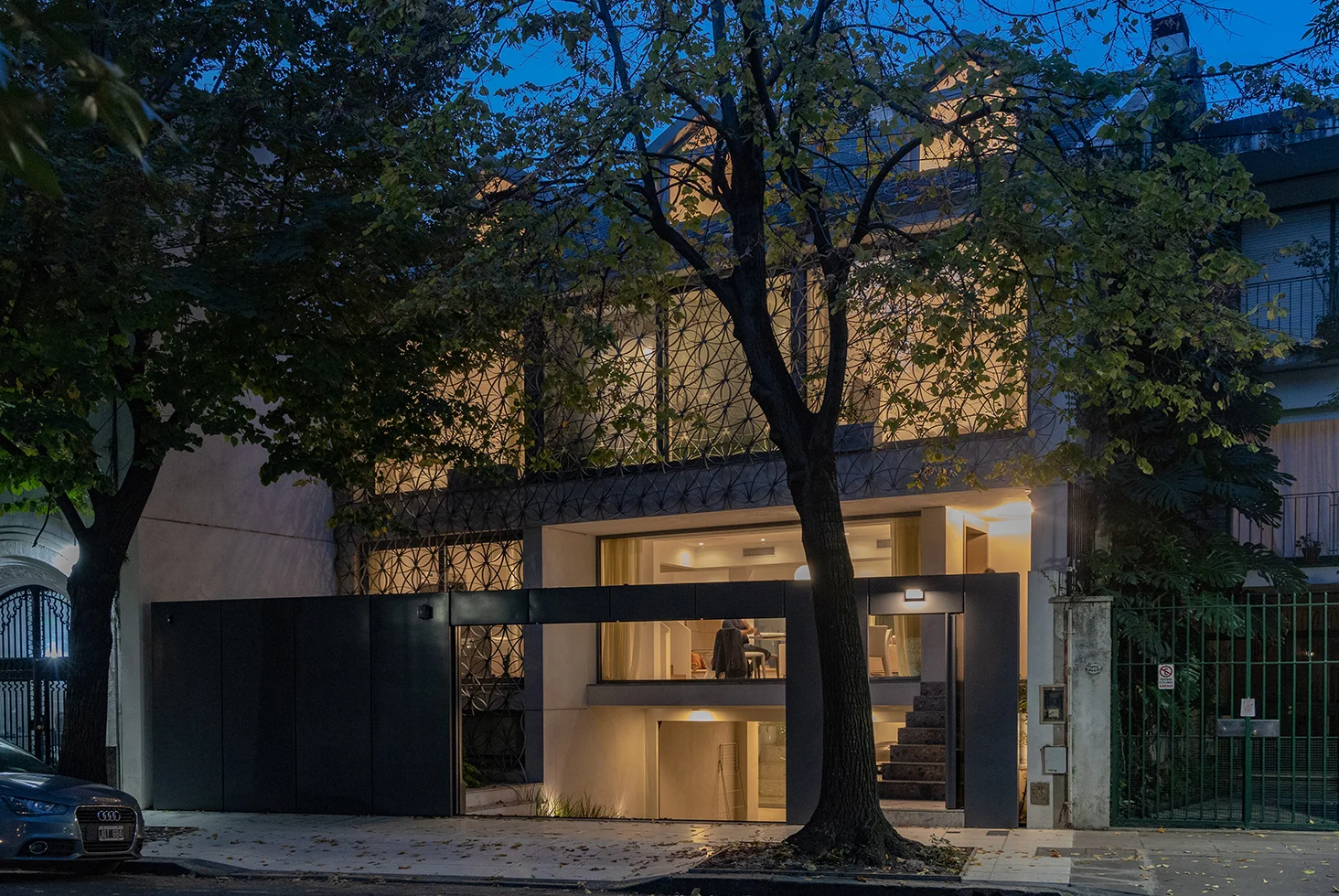 Casa Castex exterior at night with trees and large windows.